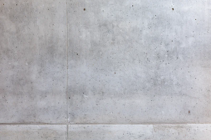 Close-up of a bare concrete wall filling the frame with visible seams and speckled texture