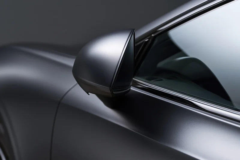 Close-up of a dark matte black luxury car exterior showing the sideview mirror and door panel