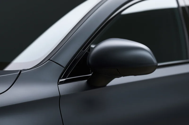 Close-up of a dark matte black luxury car exterior showing the side mirror and door panel