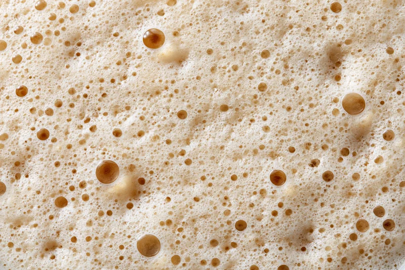 Close-up of coffee foam surface with bubbles and texture filling the frame