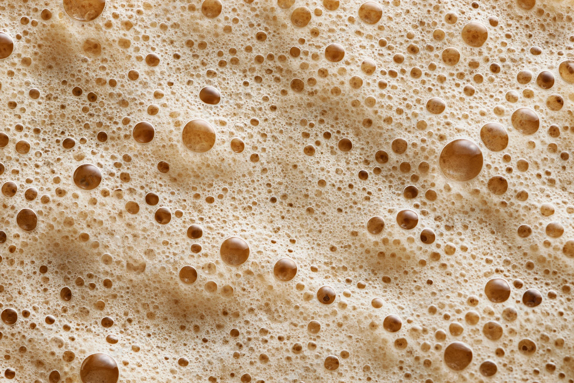 Close-up of coffee foam surface with bubbles and texture filling the frame
