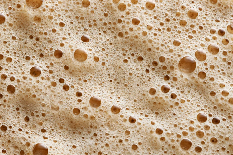 Close-up of coffee foam surface with bubbles and texture filling the frame
