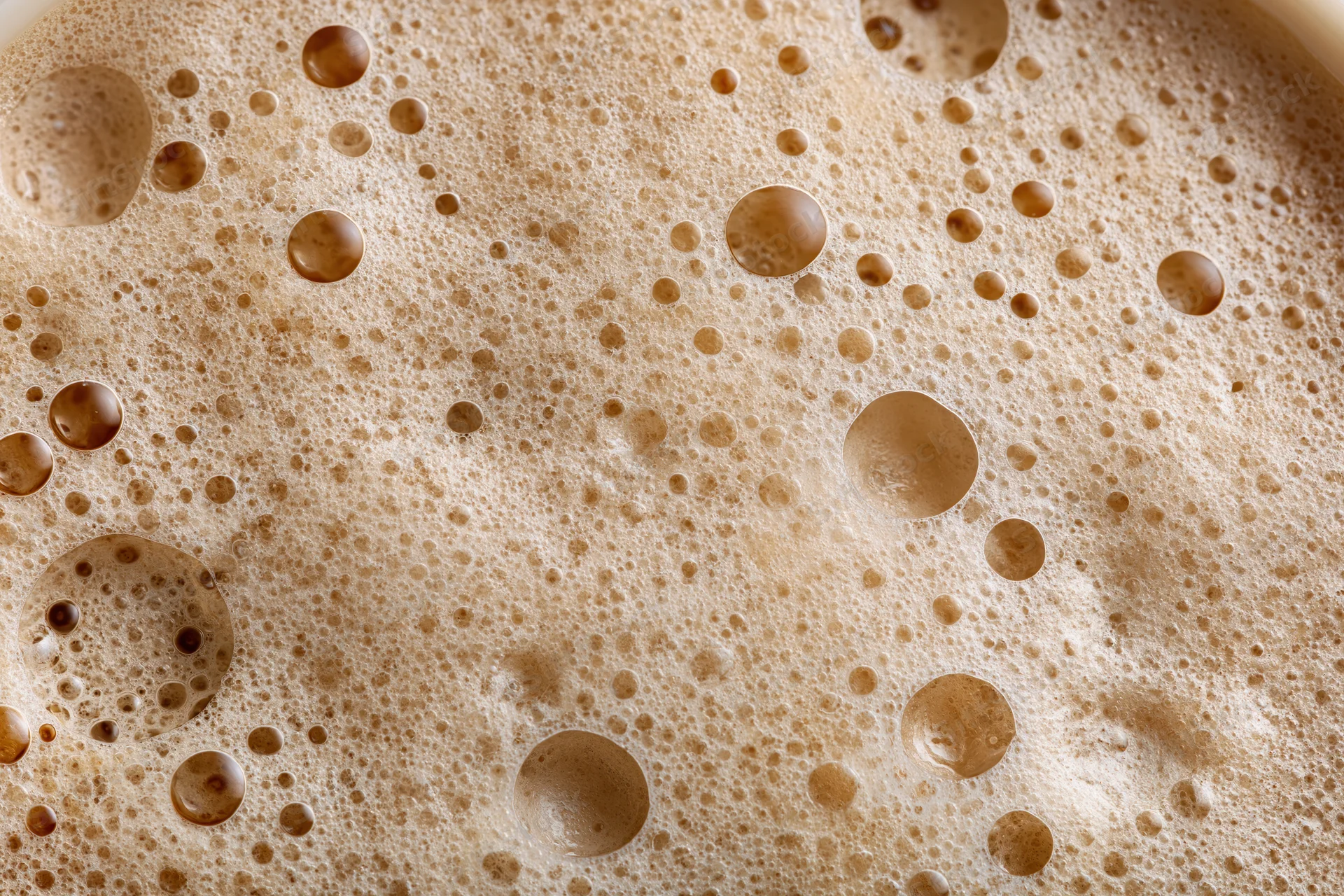 Close-up of coffee foam surface with bubbles and texture filling the frame