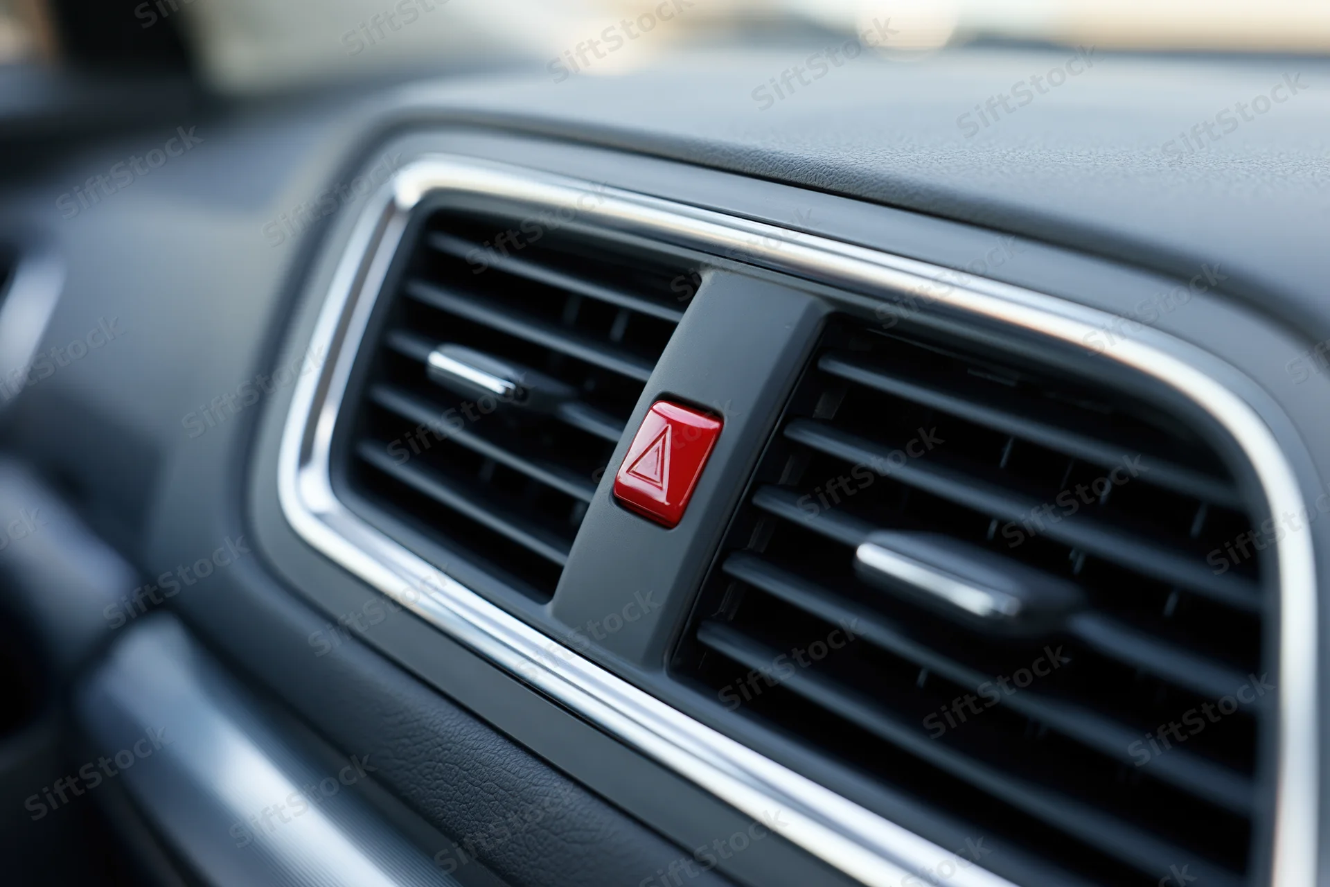 Close-up of a modern car dashboard center vent with red hazard warning button