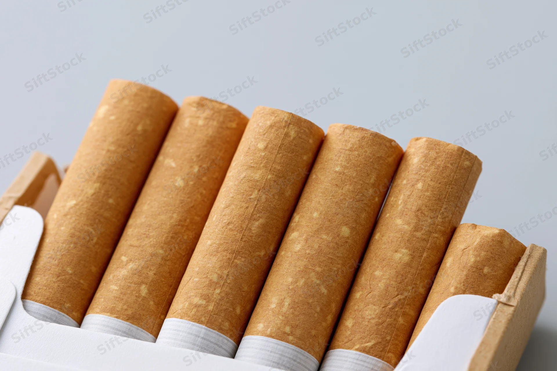 Close-up of cigarettes in an open pack on a plain background