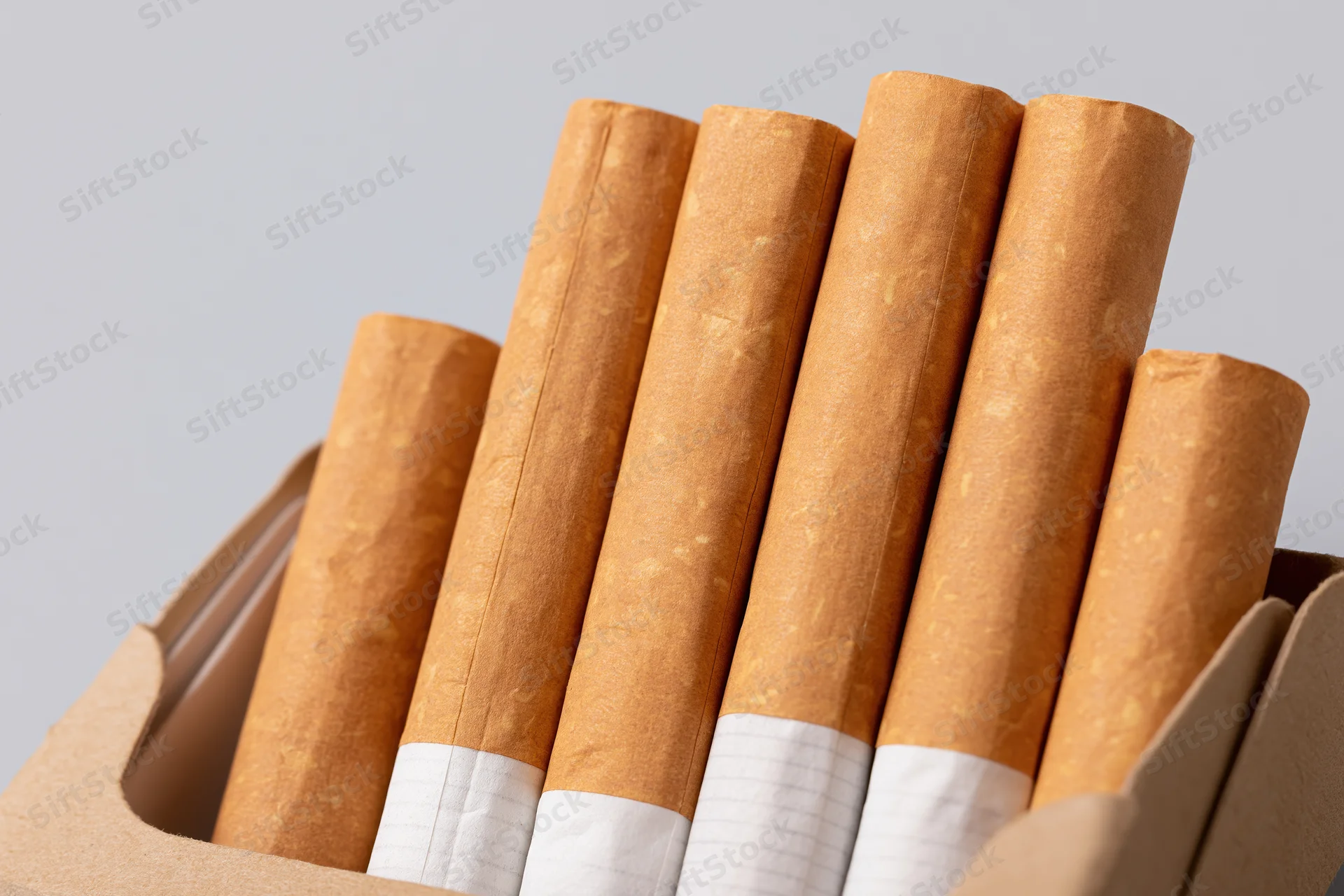 Close-up of cigarettes in an open pack against a plain background