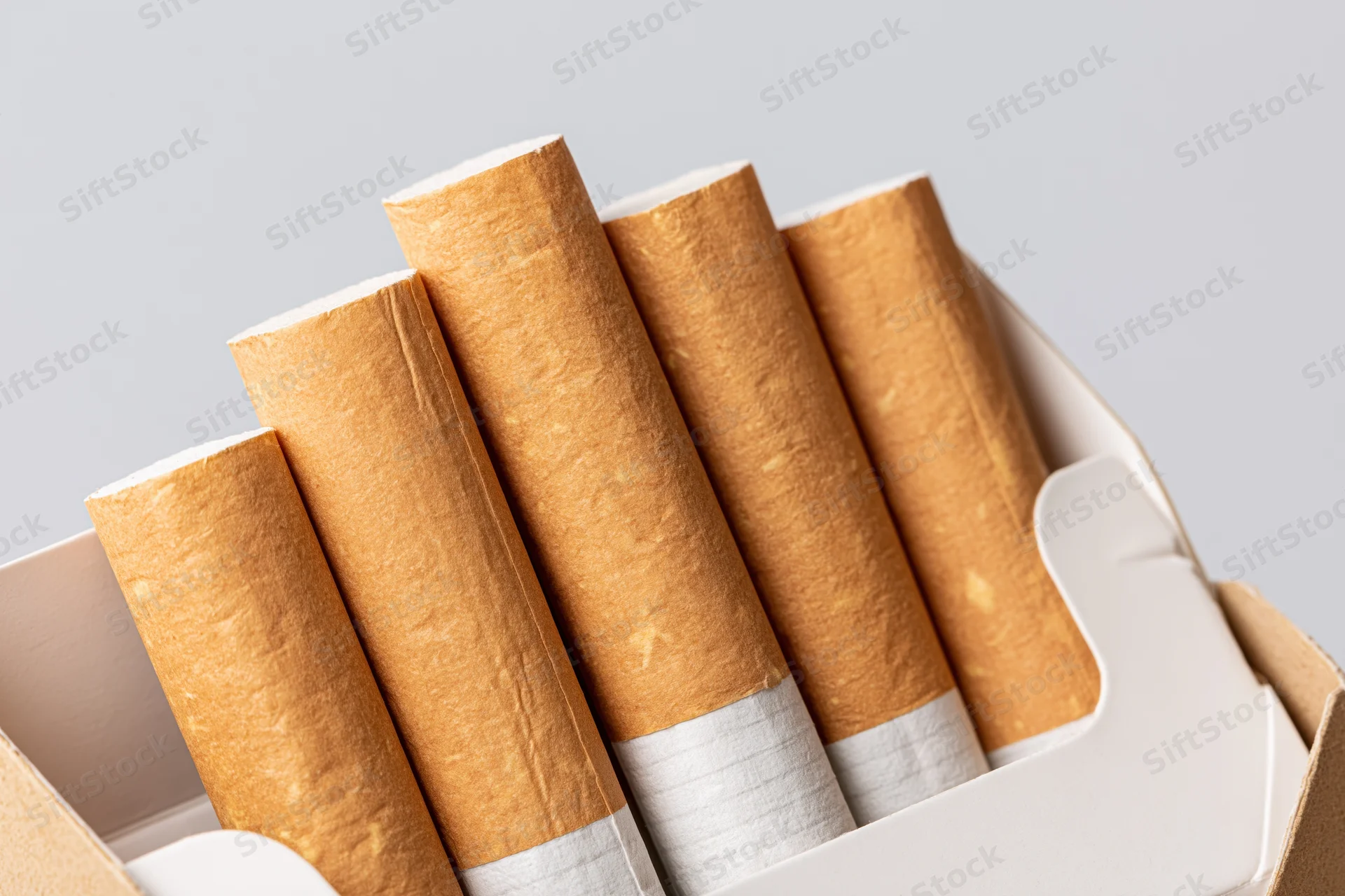 Close-up of cigarettes in an open pack showing filter tips and brown paper wrapping