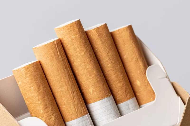 Close-up of cigarettes in an open pack showing filter tips and brown paper wrapping