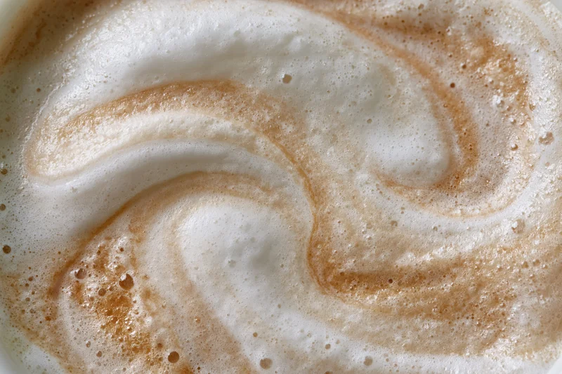 Close-up overhead view of steamed milk foam surface in a coffee drink