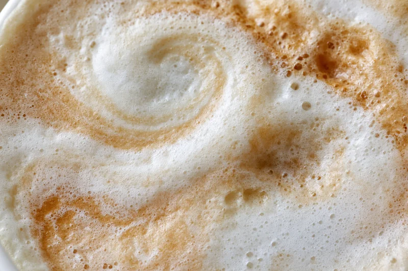 Close-up overhead view of steamed milk foam surface in a coffee drink
