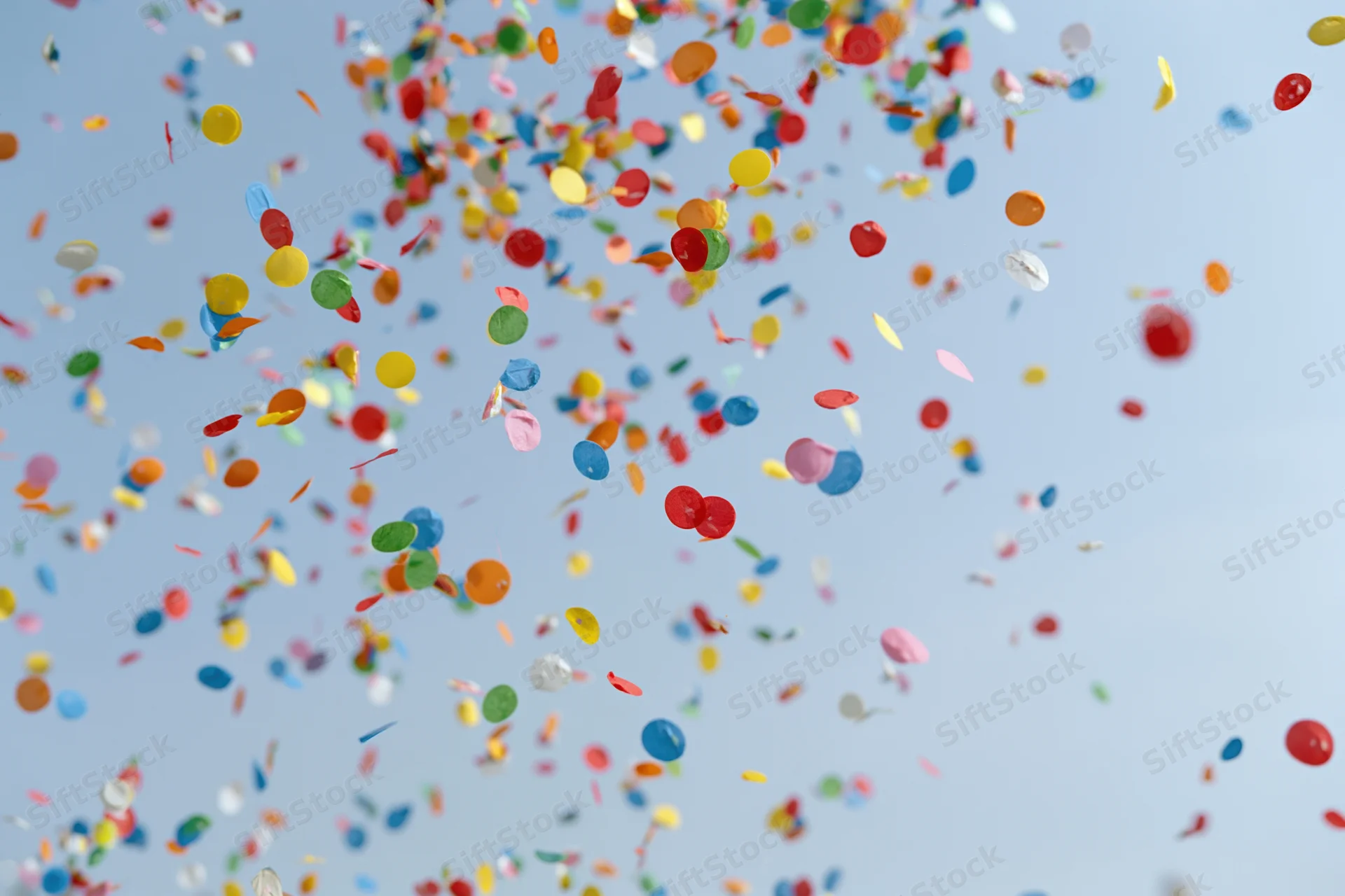 Colorful confetti floating upward against a clear sky during a celebration