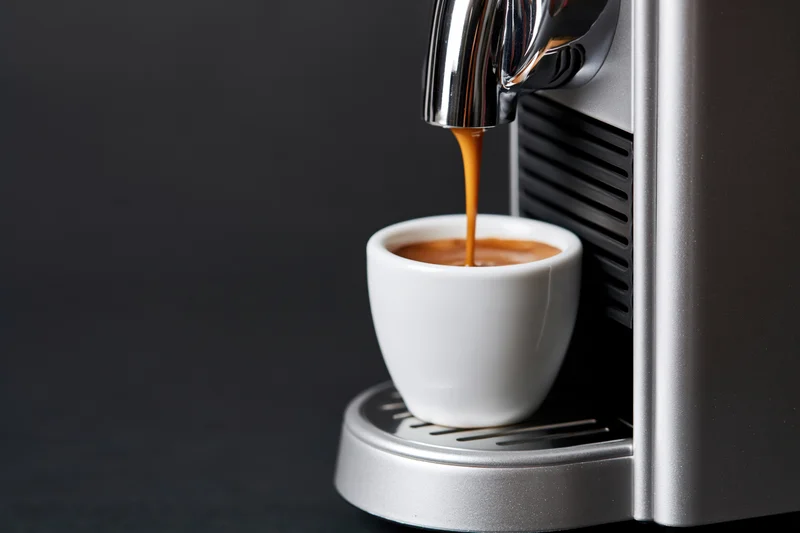 Espresso machine dispensing coffee into a white cup on a dark surface