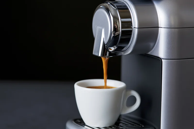 Espresso machine dispensing coffee into a white cup on a dark countertop