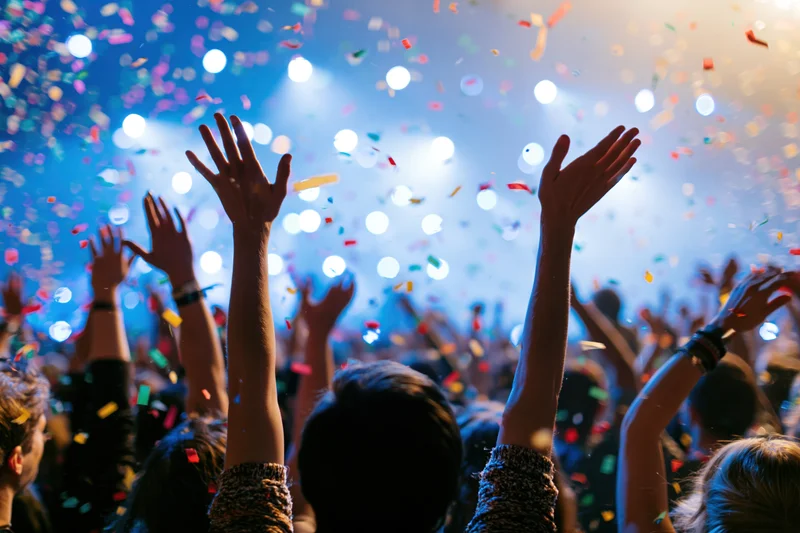 Concert crowd with arms raised at colorful live music event