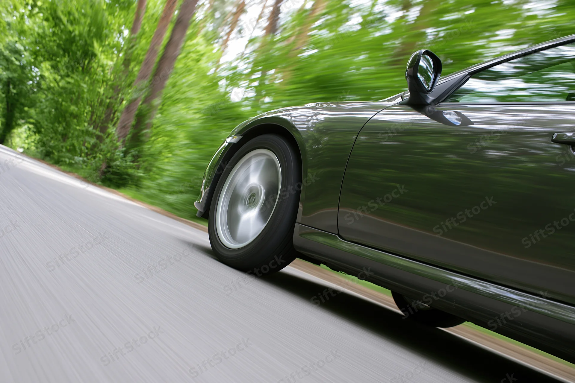 Dark metallic sports car accelerating along a tree-lined road