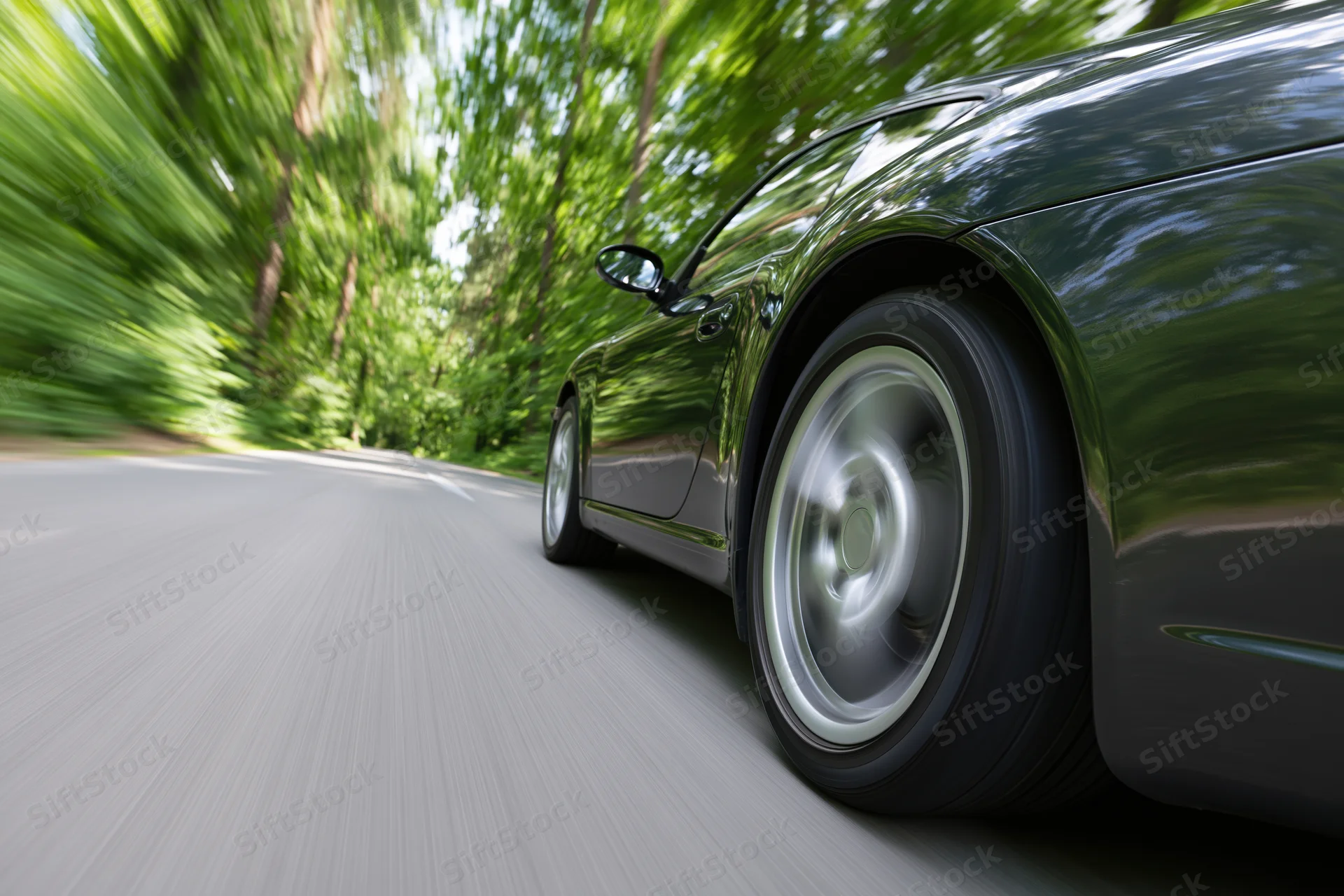 Dark metallic sports car accelerating on tree-lined road