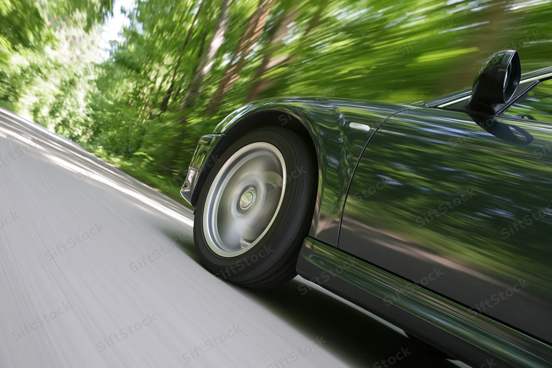 Dark metallic sports car accelerating along tree-lined road
