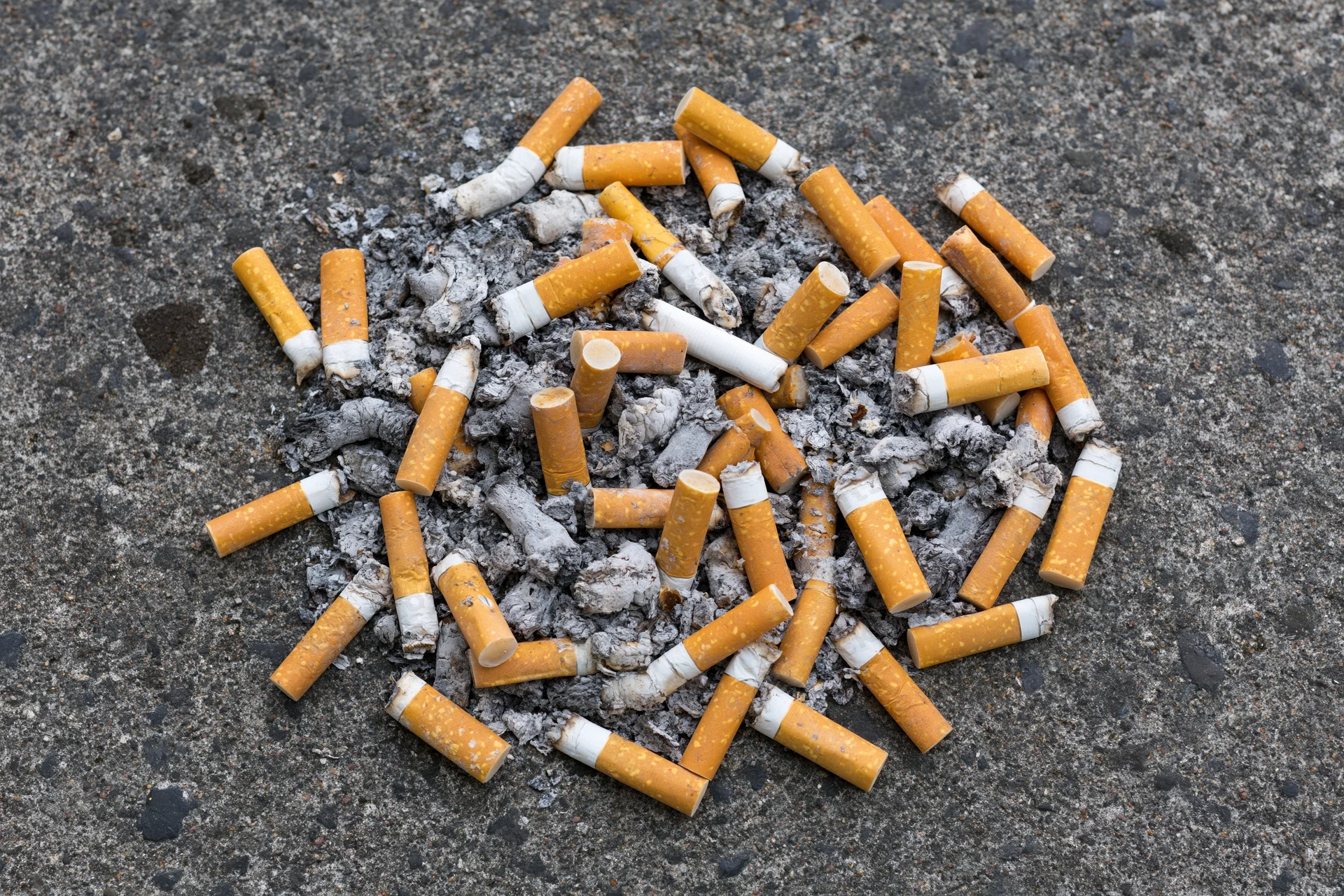 Cigarette butts and ash scattered on pavement surface