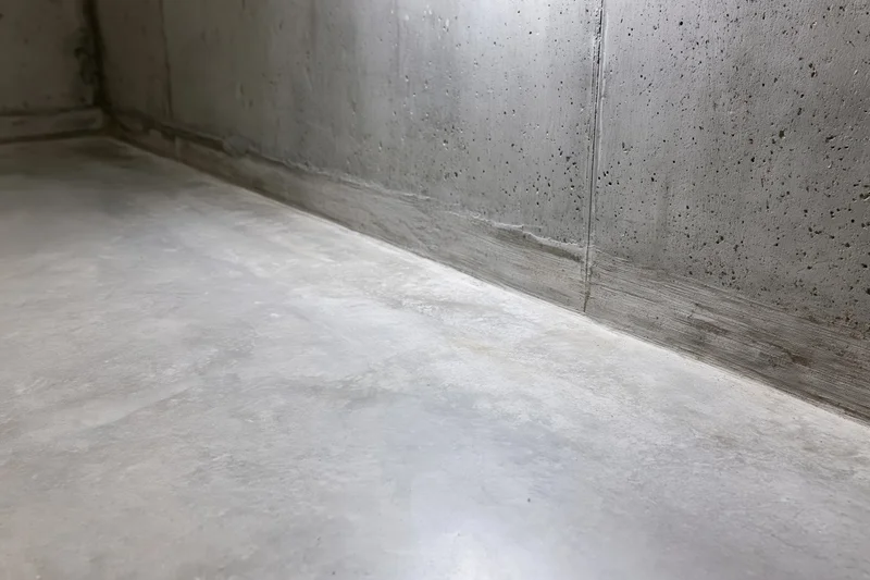 Polished concrete floor meeting gray wall in empty industrial room interior