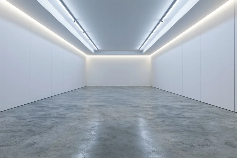 Empty modern gallery interior with white walls and concrete floor under linear ceiling lights