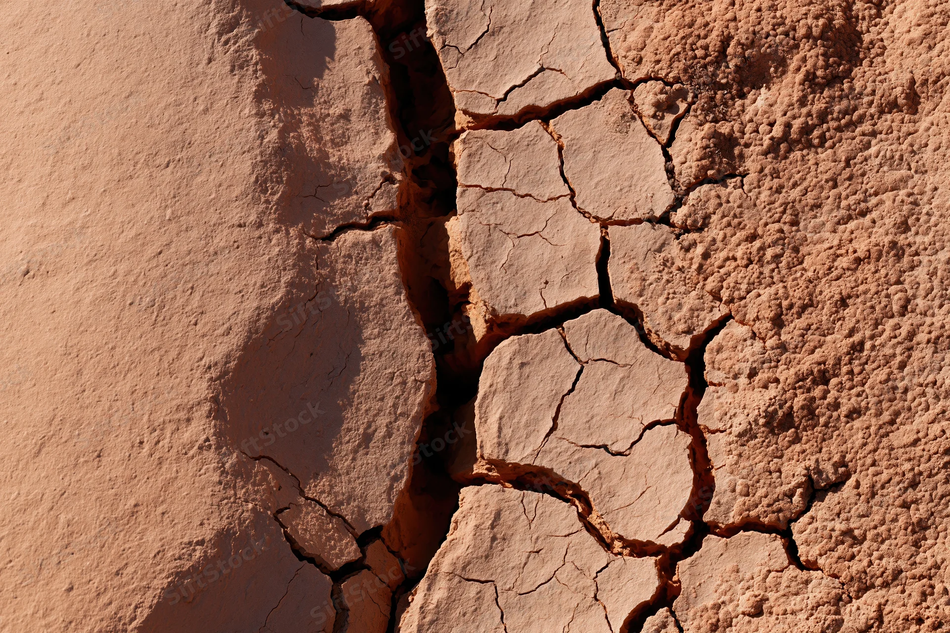Cracked dry earth surface in extreme closeup showing deep fissures and soil texture