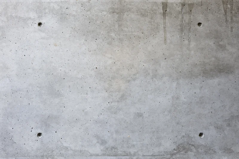 Flat concrete wall surface with small holes and stains filling the frame