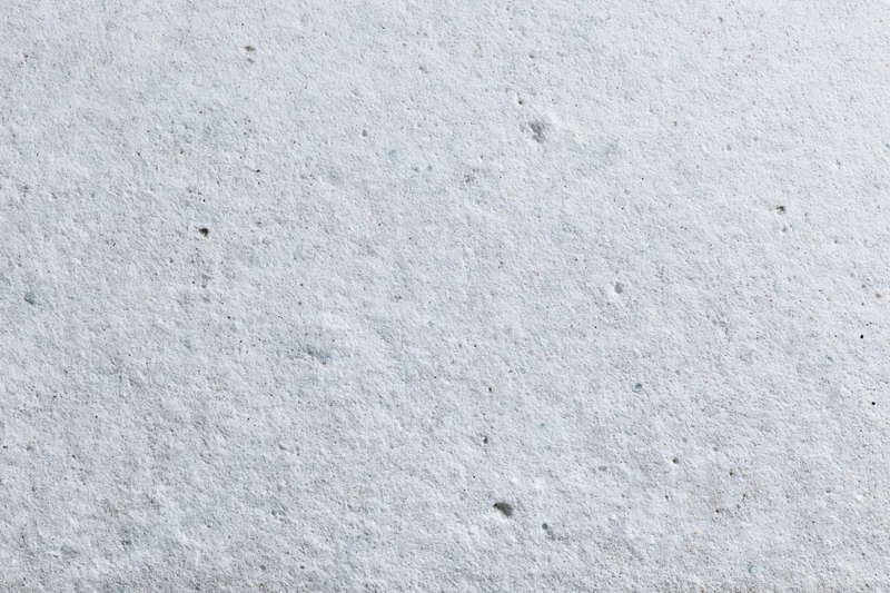 Close-up of a smooth gray concrete surface with small speckles and pores
