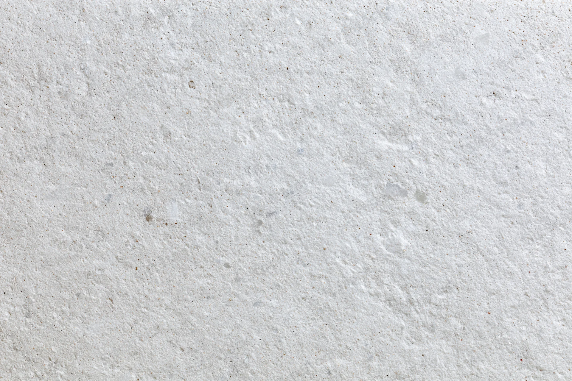 Close-up of a white concrete surface with rough texture and speckled pattern