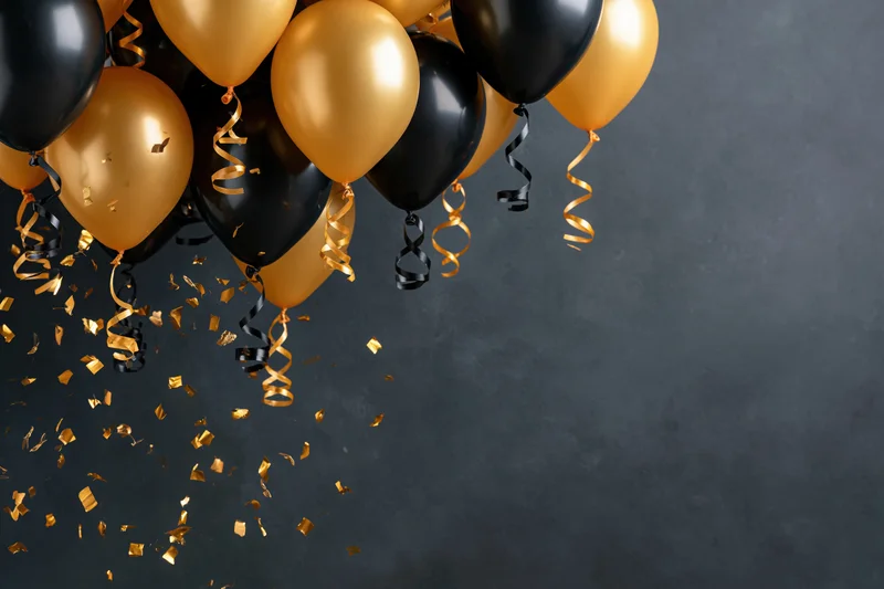 Gold and black helium balloons with falling confetti and streamers against a dark gray textured background