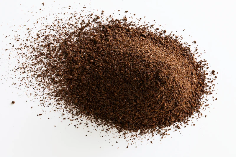 Heap of ground coffee powder scattered on white surface
