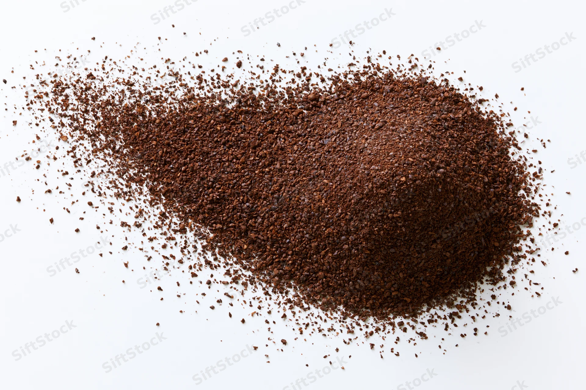 Ground coffee powder scattered and exploding outward from a cup