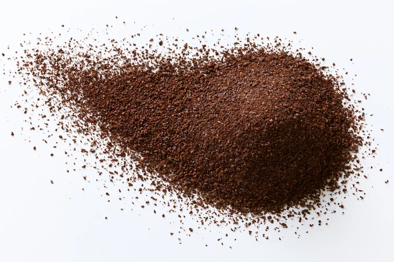 Ground coffee powder scattered in a pile on white background