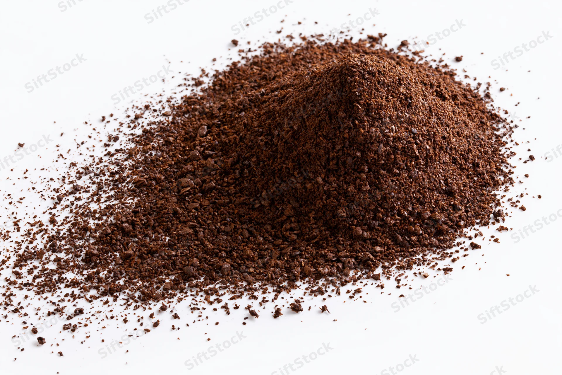 Mound of ground coffee powder scattered on white surface