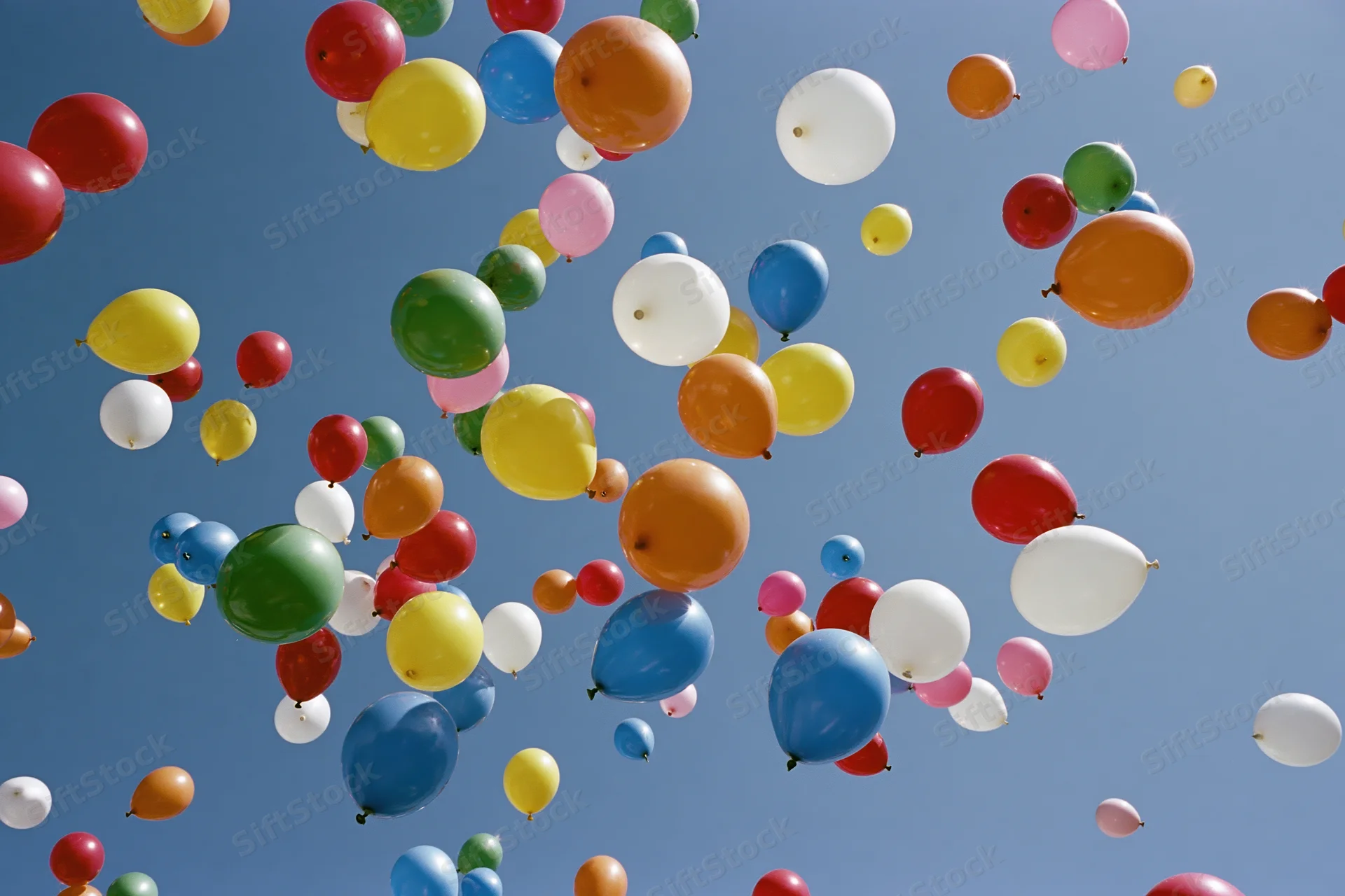 Multicolored balloons floating upward in open sky during celebration event