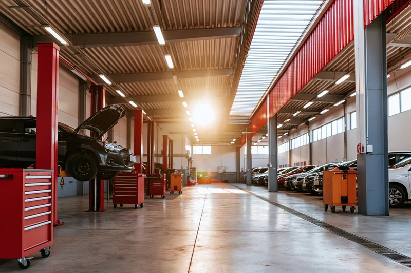 Automotive service bay interior with cars on lifts and tool chests along the sides