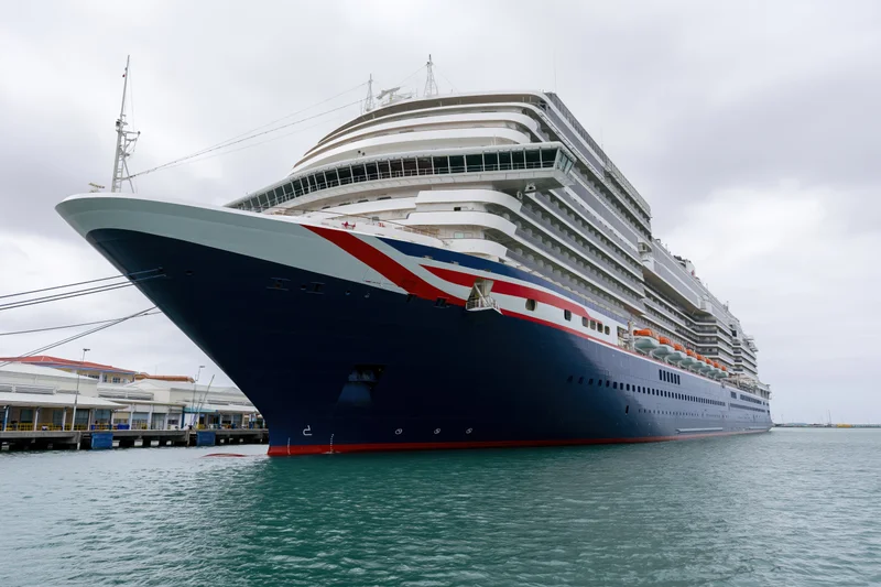Large modern cruise ship docked at port with bow facing camera