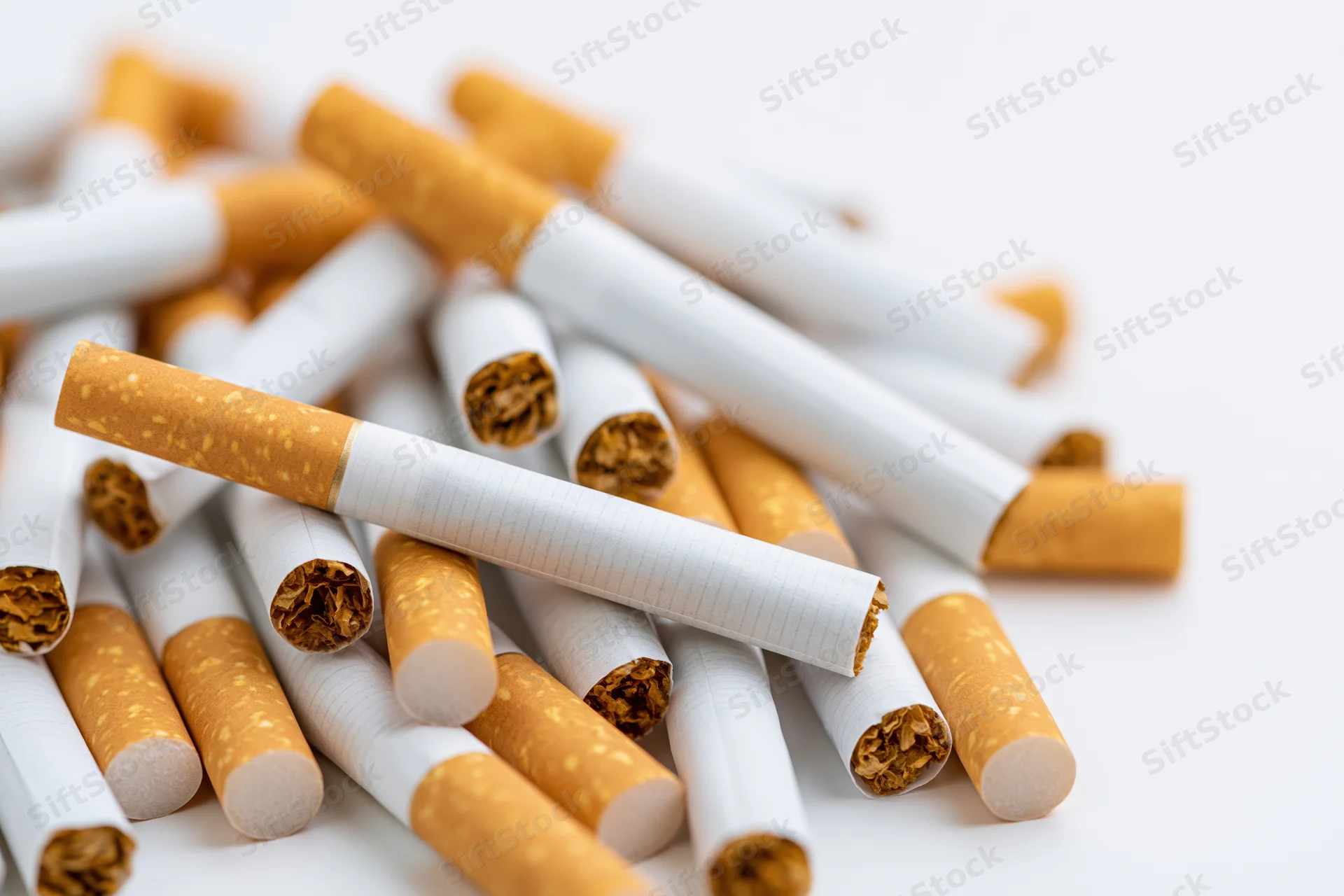 Loose cigarettes scattered in a pile on a white surface