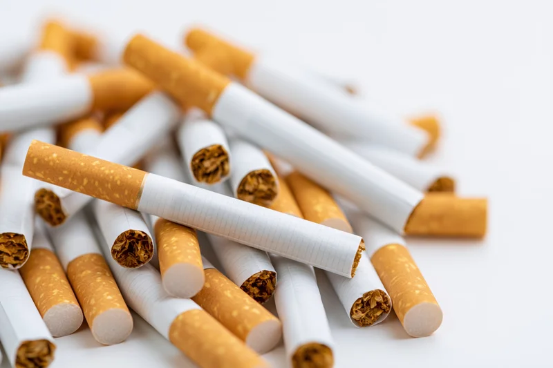 Loose cigarettes scattered in a pile on a white surface