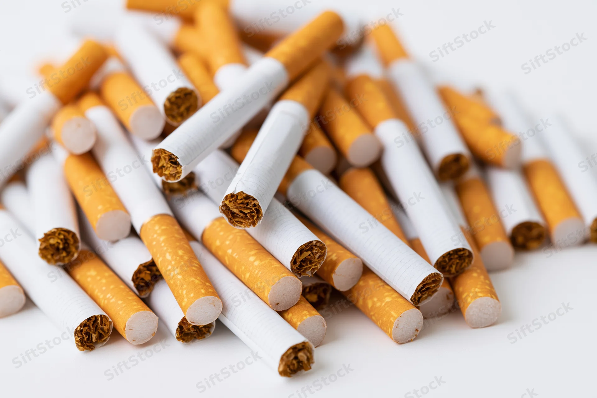 Loose cigarettes scattered in a pile on a white surface