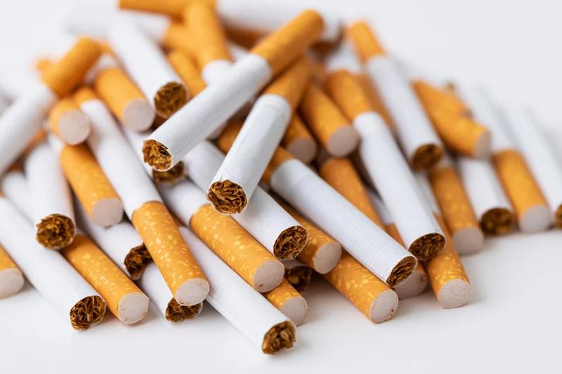 Loose cigarettes scattered in a pile on a white surface