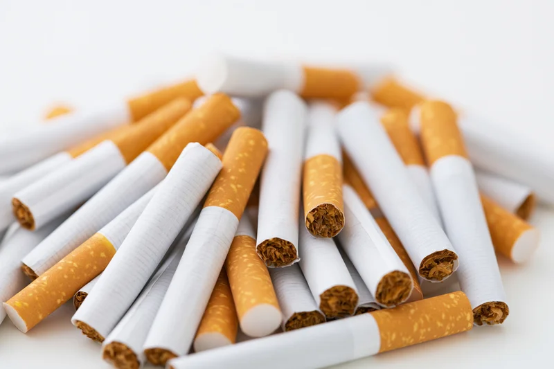Loose cigarettes scattered in a pile on a white surface