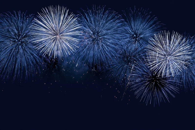 Blue and white fireworks bursting across the night sky in a festive display