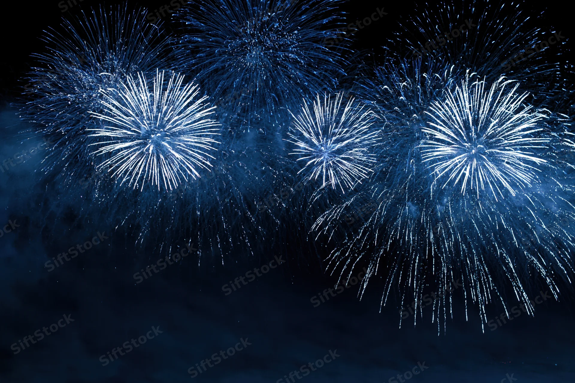 Blue and white fireworks bursting across the night sky in a celebratory display