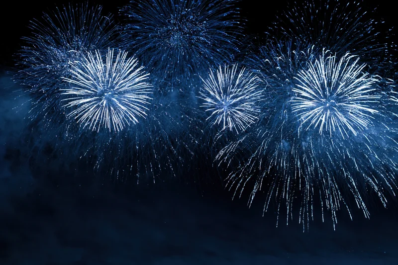 Blue and white fireworks bursting across the night sky in a celebratory display