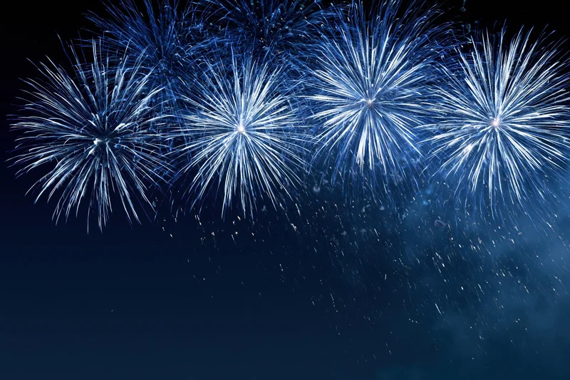 Blue and white fireworks bursting across the night sky in a festive display