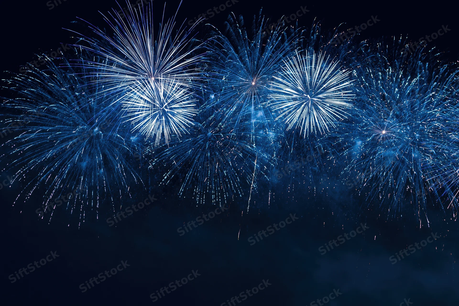 Blue and white fireworks bursting across the night sky during a celebration event