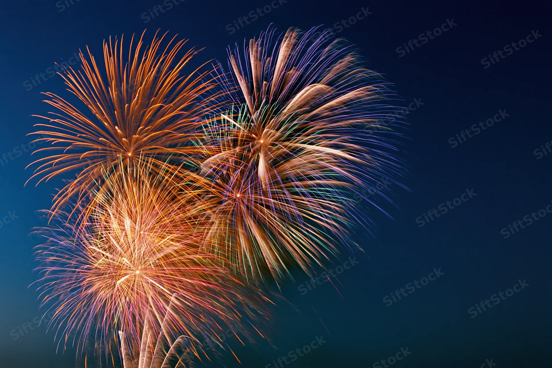 Multiple fireworks bursting in the night sky during a celebration