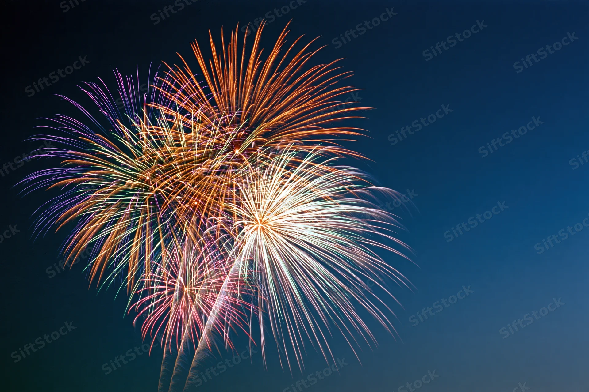 Multiple fireworks bursting simultaneously in the night sky