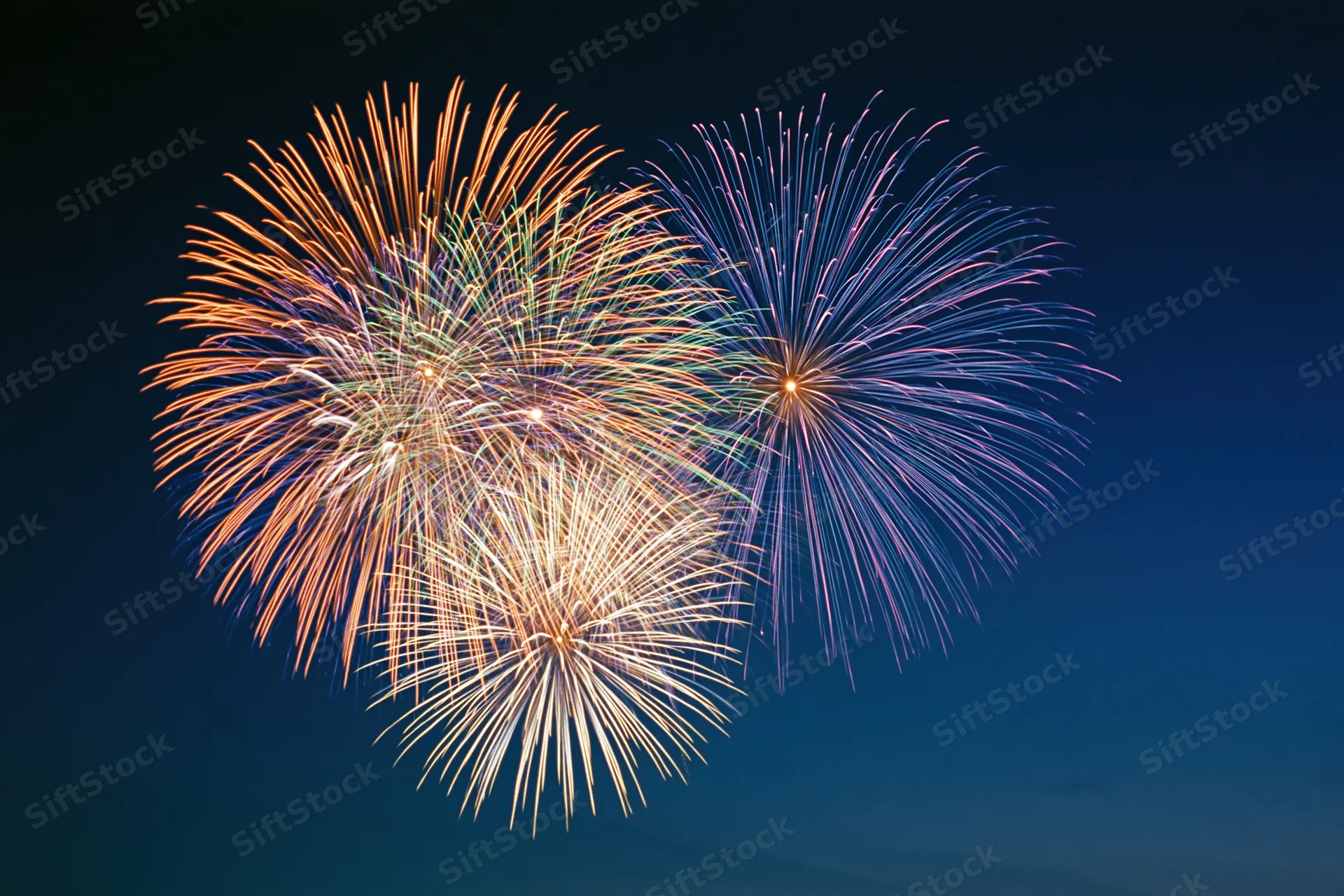 Multiple fireworks bursting simultaneously in the night sky