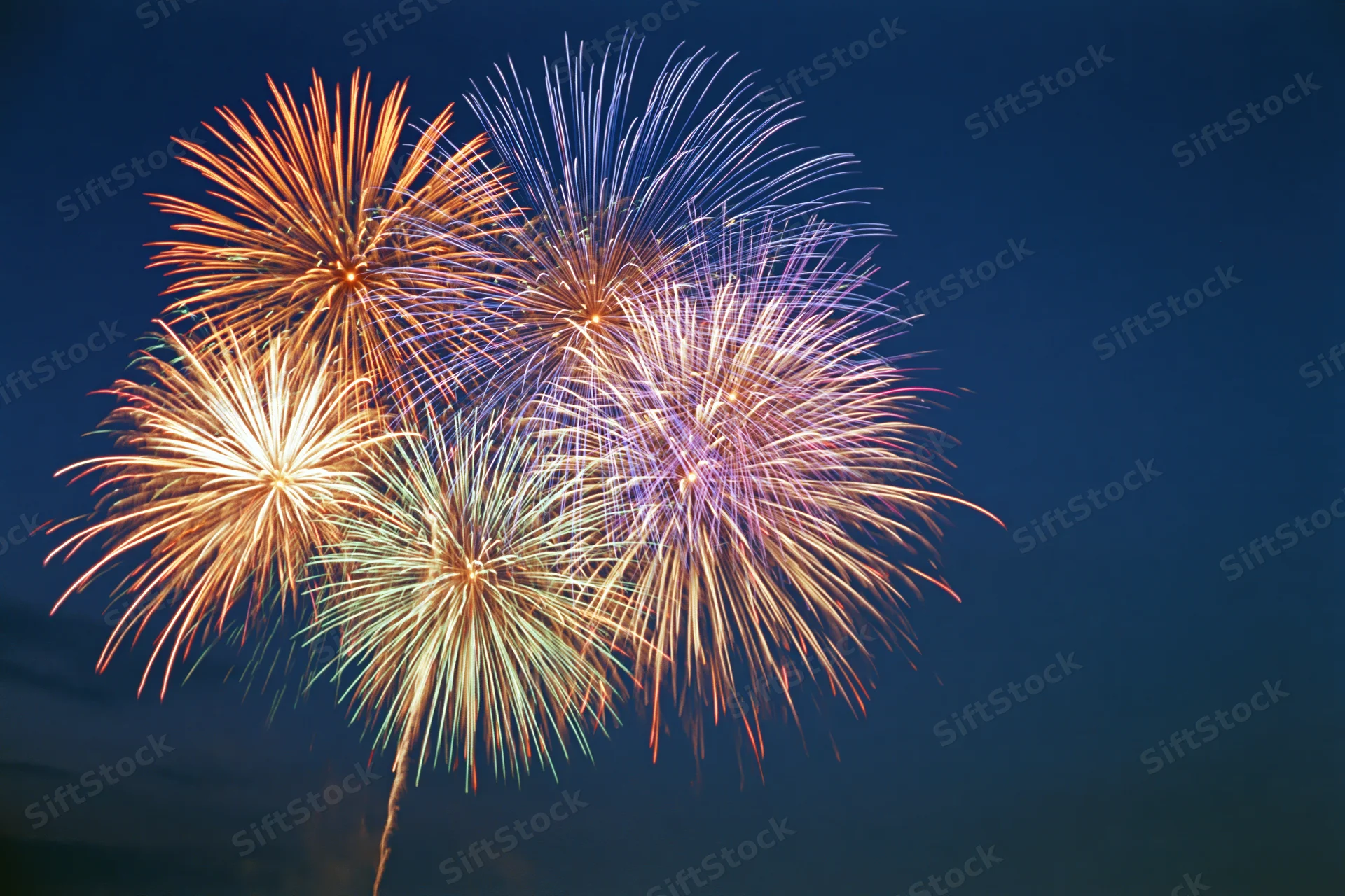 Multiple fireworks bursting simultaneously in the night sky